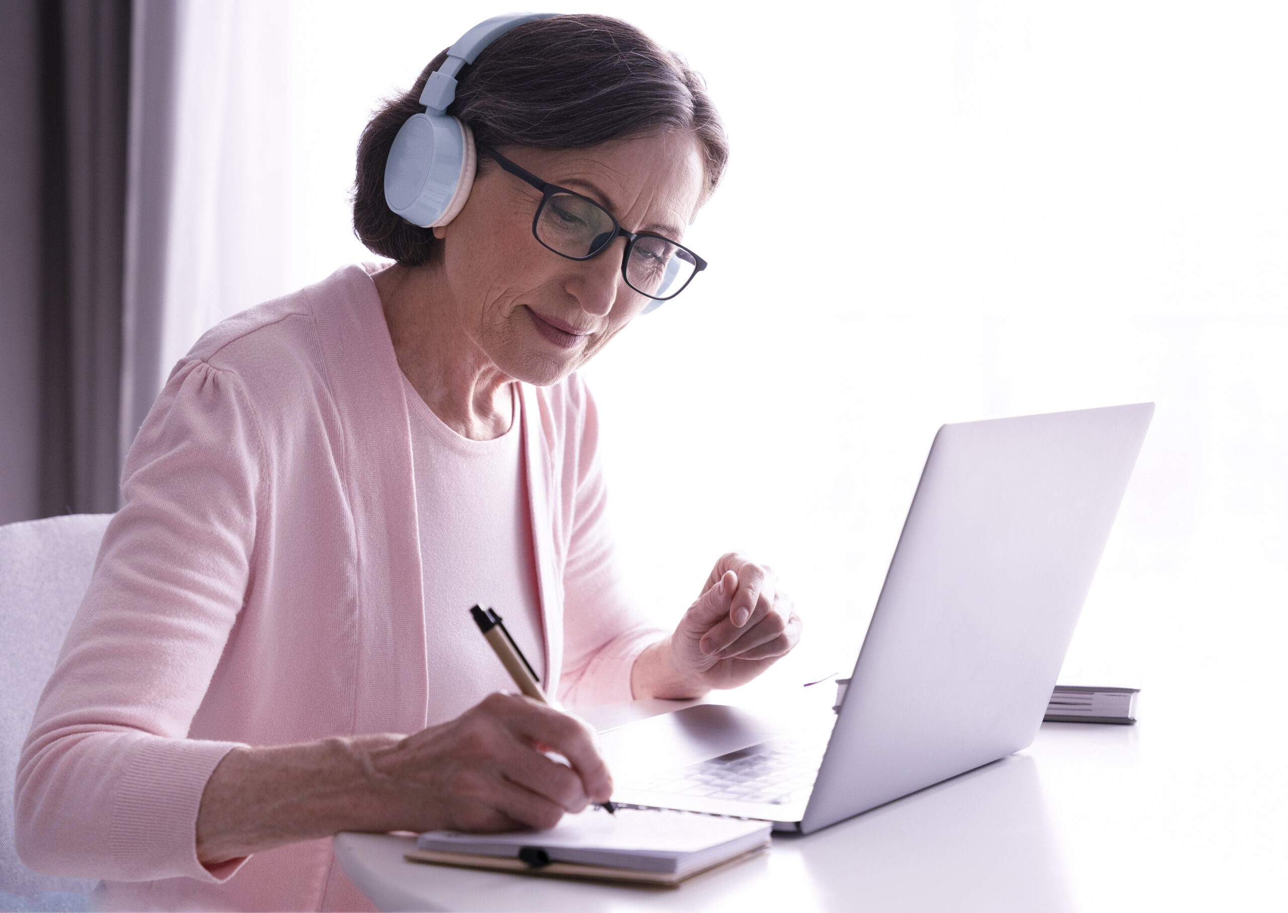 Mujer adulta realizando un curso online desde casa con ordenador y cuaderno